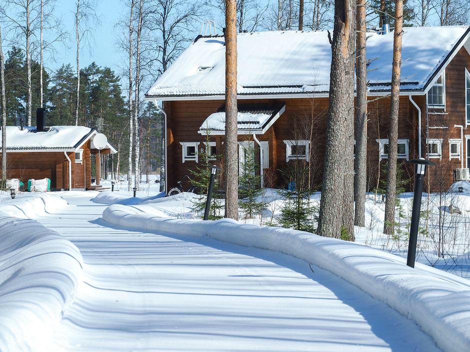 Luminen tie mökille Saimaan rannalla, Suomi: puinen mökki ja rantasauna talvisen metsän keskellä aurinkoisena päivänä